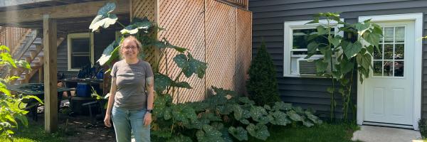Gretchen standing in a yard with a large squash plant